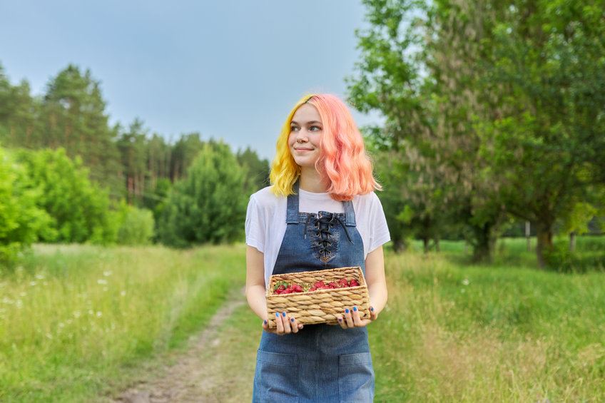 Female student working on a farm holding strawberries